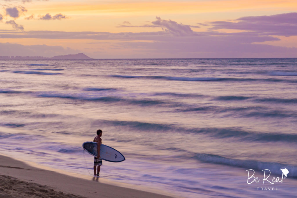 With Honolulu in the background, a surfer surveys the waves at White Plains Beach on Oahu, Hawaii