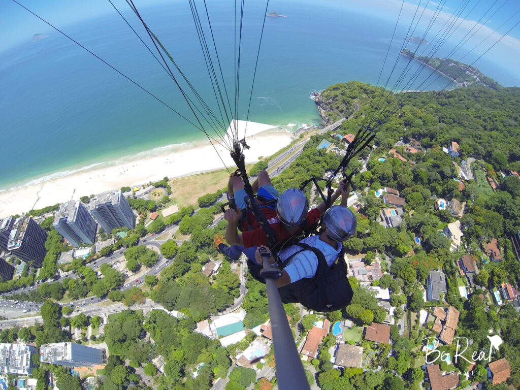 Two men paraglide over the outskirts of Rio de Janeiro