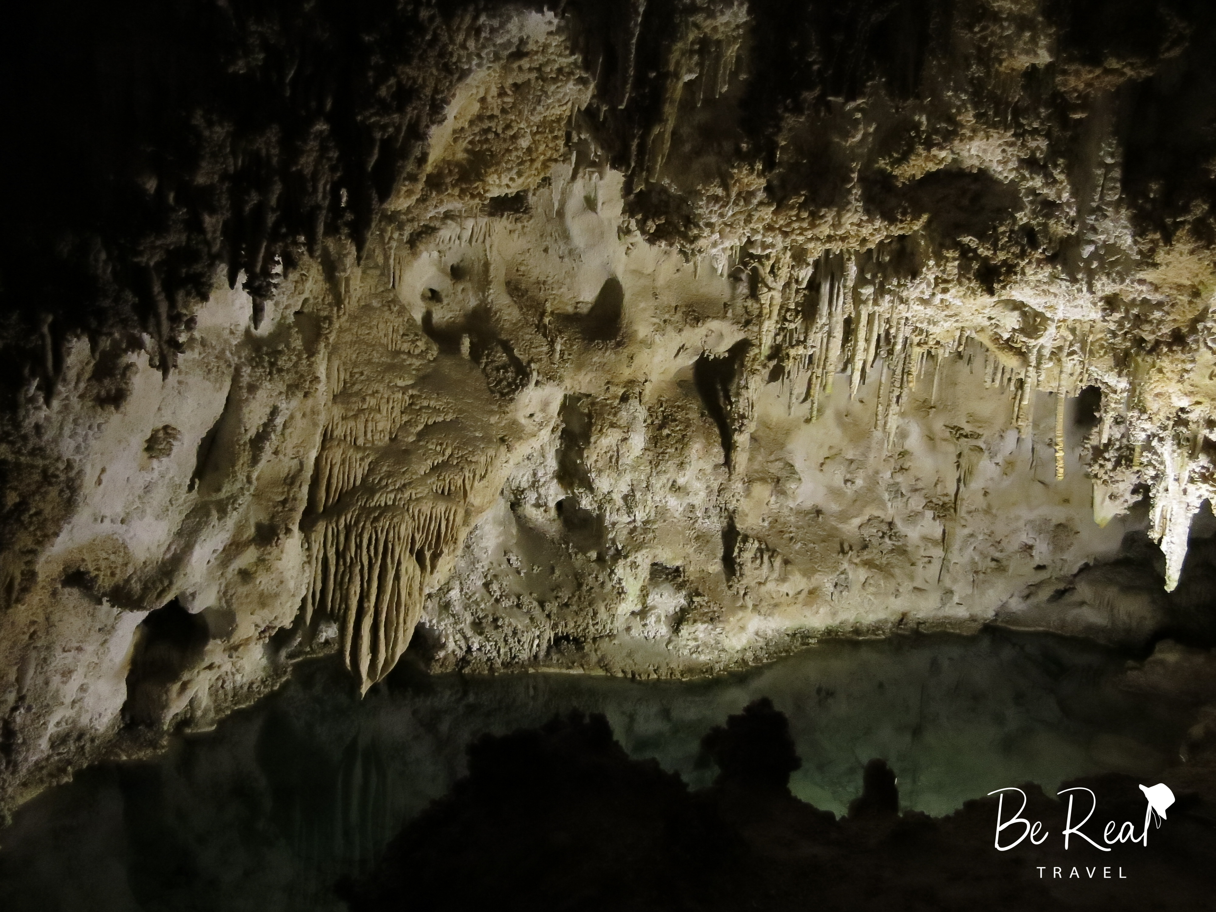 Mineral formations hang above cave water at Carlsbad Caverns National Park