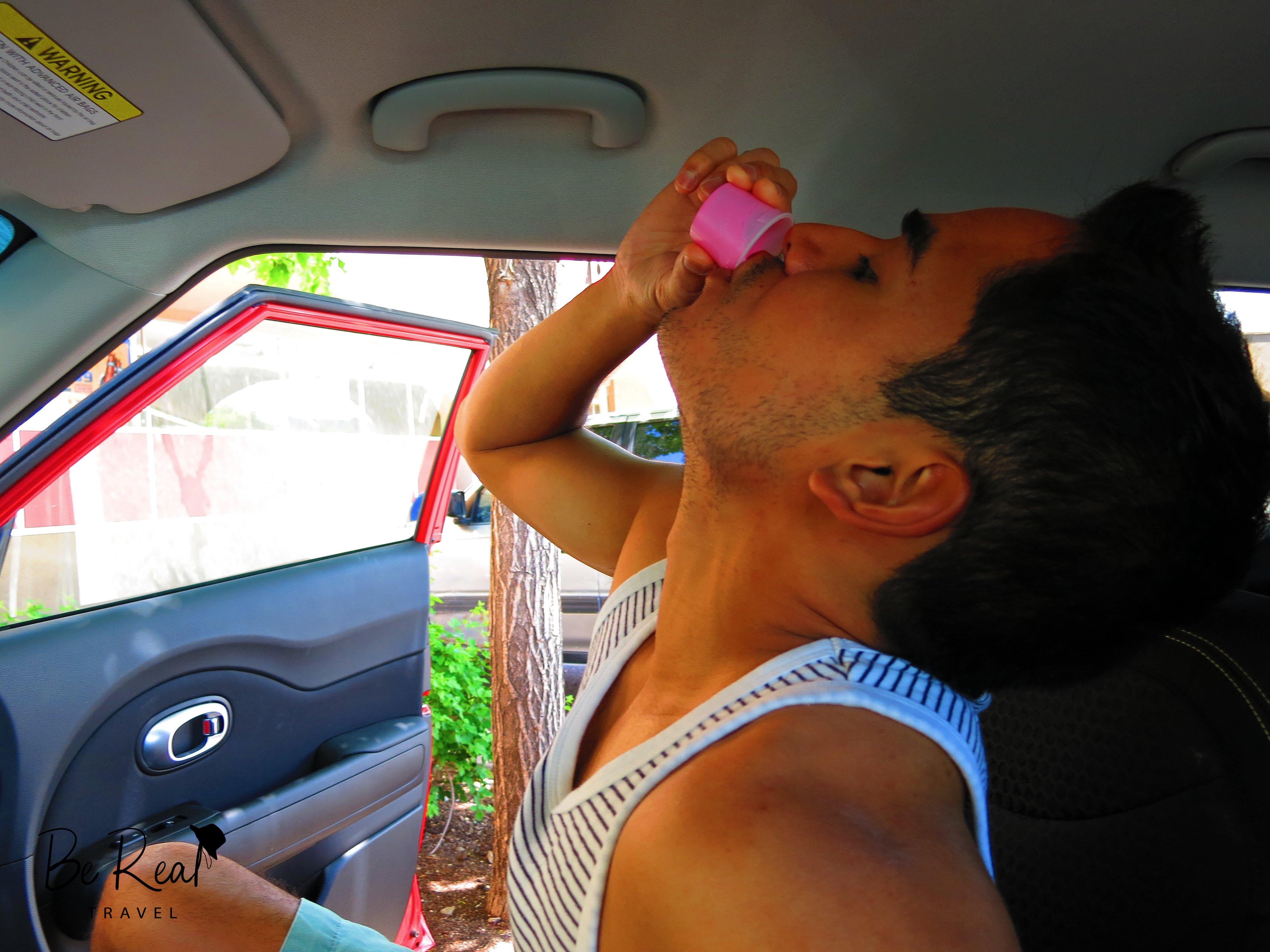A man takes a shot of Pepto Bismol, in a car, in Santa Fe, New Mexico