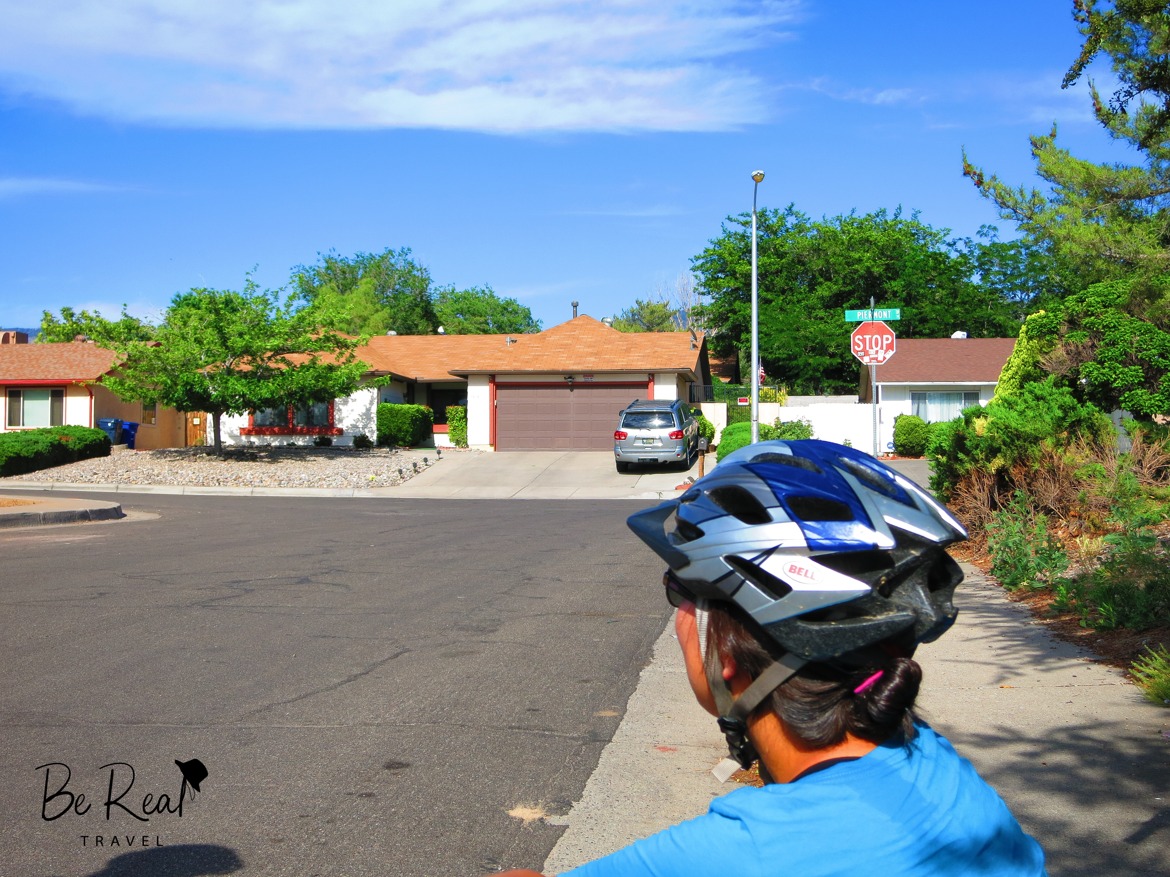 A helmet-wearing woman looks on at a suburban house; this house is where the White family lived in New Mexico Breaking Bad